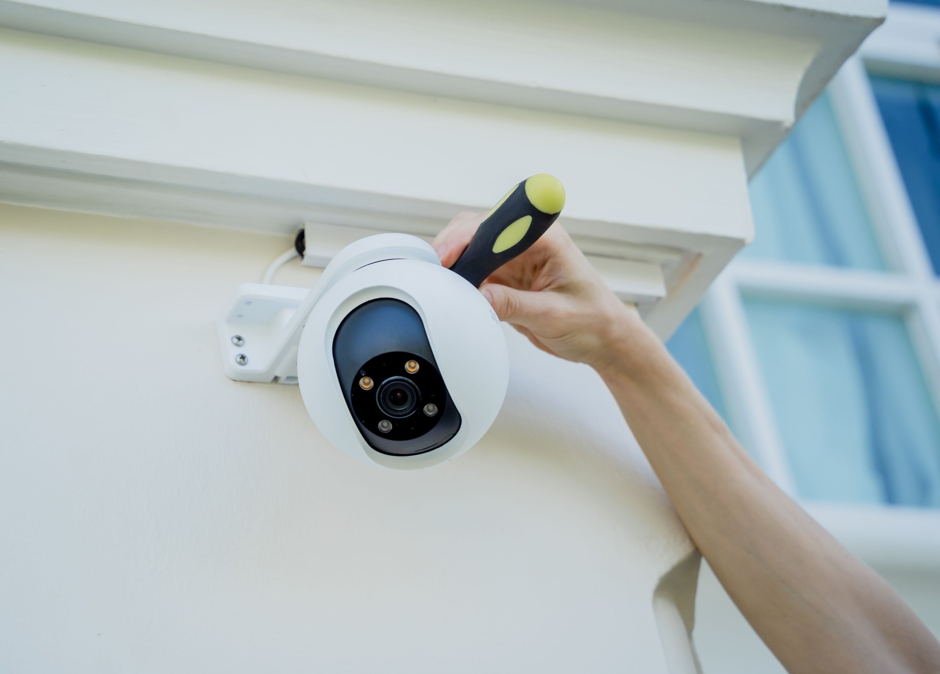 A technician installs a CCTV camera on the facade of a residential building. A technician installs a CCTV camera on the facade of a residential building.